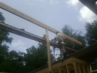Carpenter setting a ridge beam over a new addition frame — Ice Dam Removal by Roofing Brothers in Mckinney