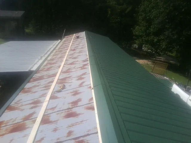 Old rusted panels beside newly installed green metal roofing — Wind Damage Roof Repair by Roofing Brothers in Mckinney