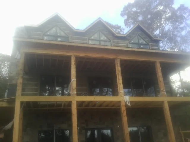Dormers and porch framing on a large log home under construction — Roof Coating work by our crew in Mckinney