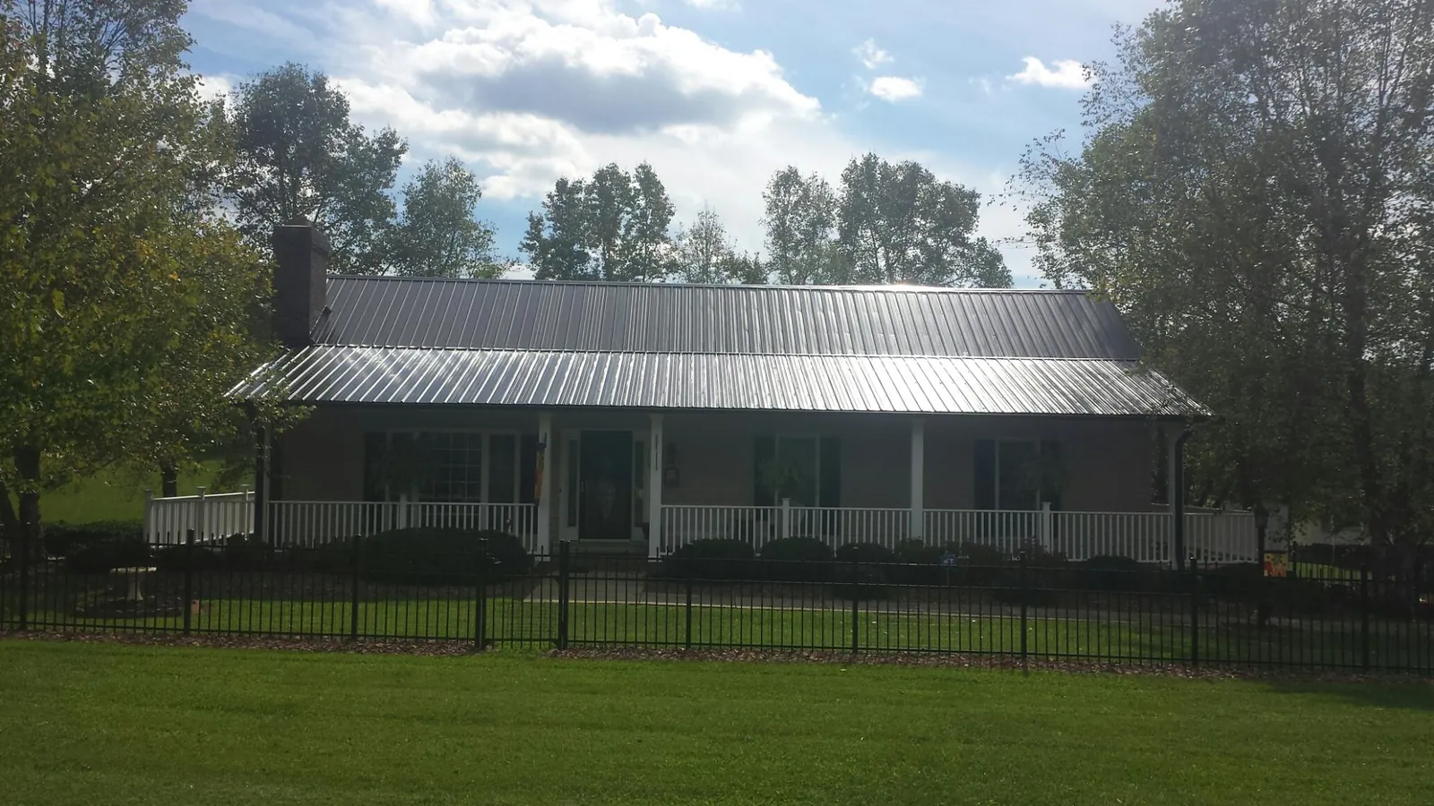 Gray metal roof on a brick ranch with a full width front porch — Gutter Guard Installation work by our crew in Mckinney