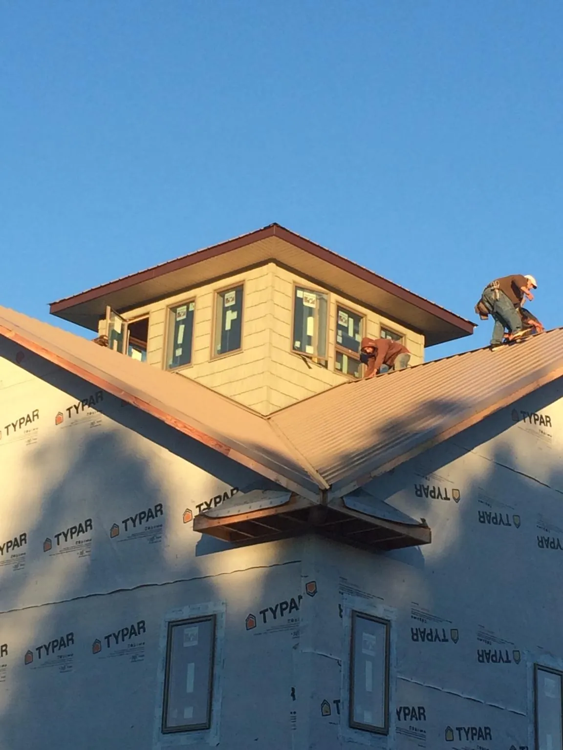 Roofers working around a rooftop cupola on a new metal roof at sunset — Roof Waterproofing in Mckinney by Roofing Brothers